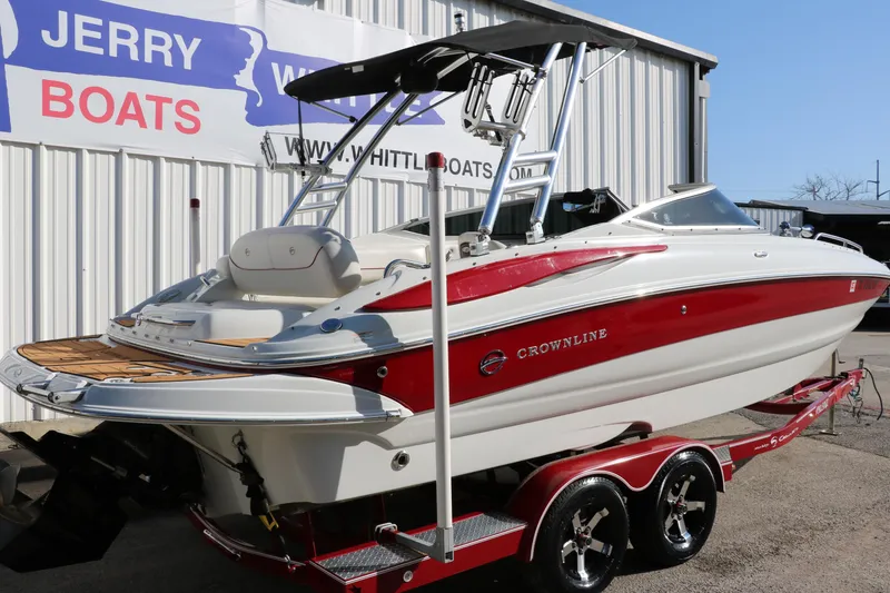 Slide: The Image of 2007 Crownline 240 EX boat on trailer, red and white, parked outside dealership. - 3