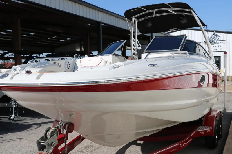 Slide: The Image of 2007 Crownline 240 EX boat with red accents on a trailer, parked outdoors. - 9