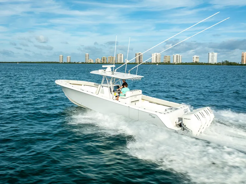 Slide: The Image of 2024 SeaVee 390B boat cruising on open water with city skyline in background. - 2