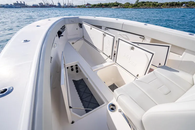 Slide: The Image of 2024 SeaVee 390B boat interior with open storage compartments, white seating, and ocean backdrop. - 25