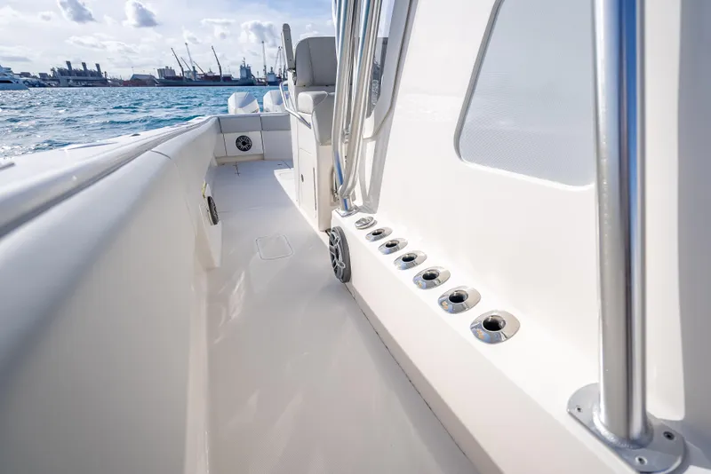 Slide: The Image of 2024 SeaVee 390B boat deck with rod holders, ocean view, and distant port skyline. - 35