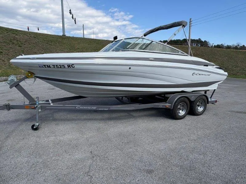 Slide: The Image of 2019 Crownline 215 SS boat on trailer, parked outdoors under cloudy sky. - 13