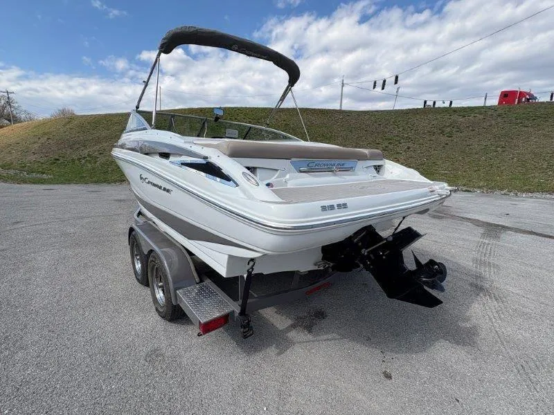 Slide: The Image of 2019 Crownline 215 SS boat on trailer, parked outdoors under cloudy sky. - 15