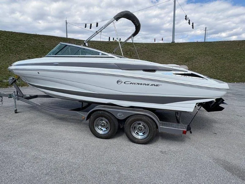 Slide: The Image of 2019 Crownline 215 SS boat on trailer, parked outdoors under cloudy sky. - 16