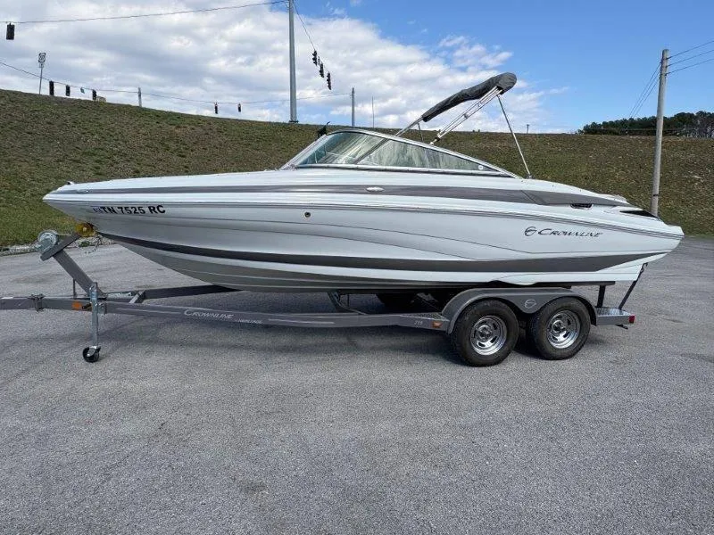 Slide: The Image of 2019 Crownline 215 SS boat on trailer, parked outdoors under a partly cloudy sky. - 18