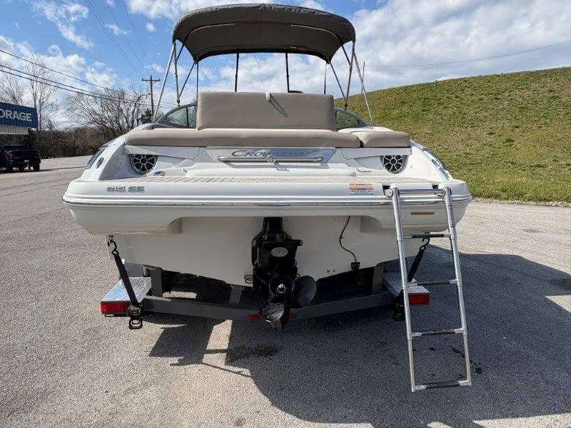 Slide: The Image of 2019 Crownline 215 SS boat with ladder, parked on pavement under a cloudy sky. - 25