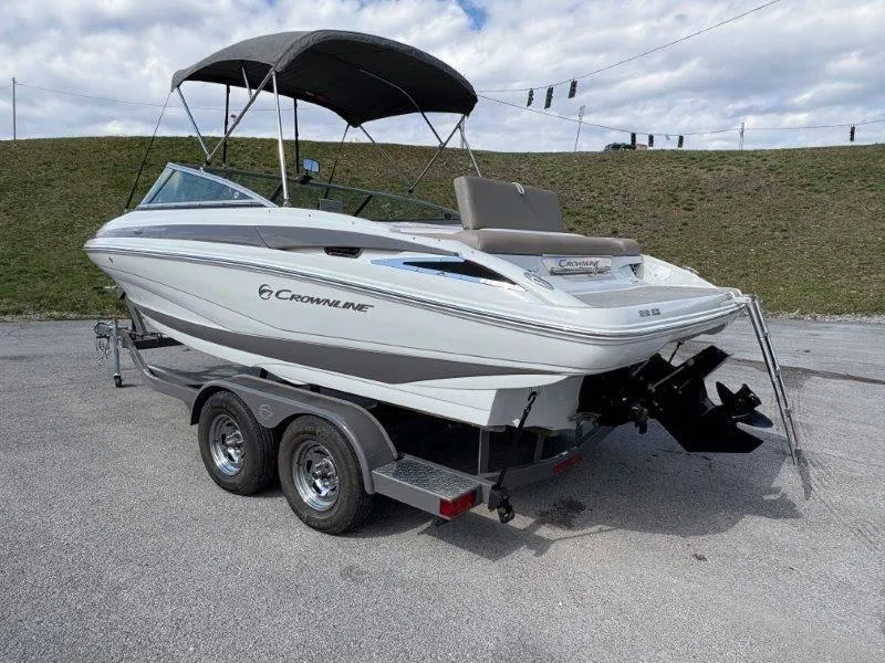 Slide: The Image of 2019 Crownline 215 SS boat on trailer, parked outdoors under cloudy sky. - 28