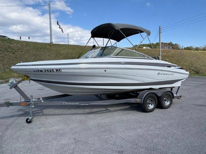 Slide: The Image of 2019 Crownline 215 SS boat on trailer, parked outdoors under a clear sky. - 29