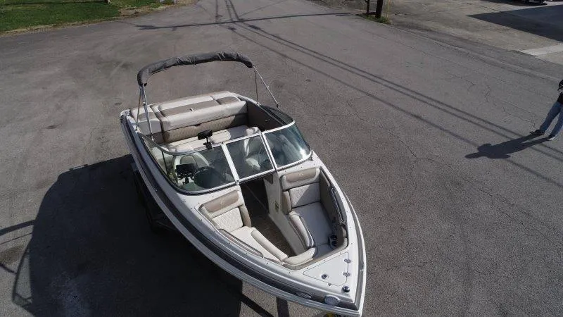 Slide: The Image of 2019 Crownline 215 SS boat with bimini top, parked on pavement. - 6