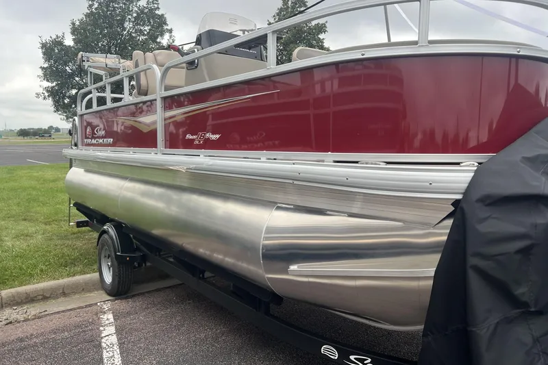 The Image of 2025 Sun Tracker Bass Buggy 18 DLX pontoon boat, red and silver, parked on grass. - 0