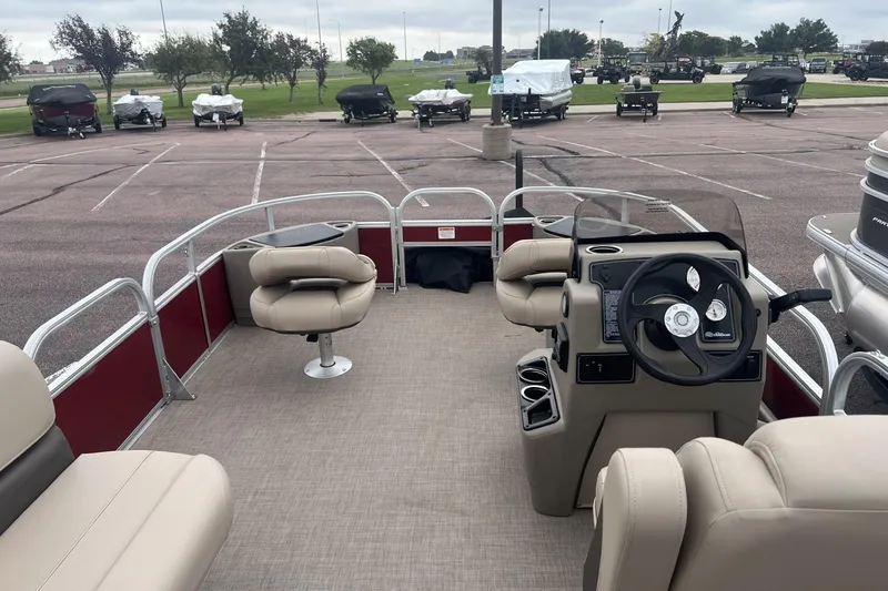 Slide: The Image of 2025 Sun Tracker Bass Buggy 18 DLX pontoon boat interior with beige seating and steering console. - 3