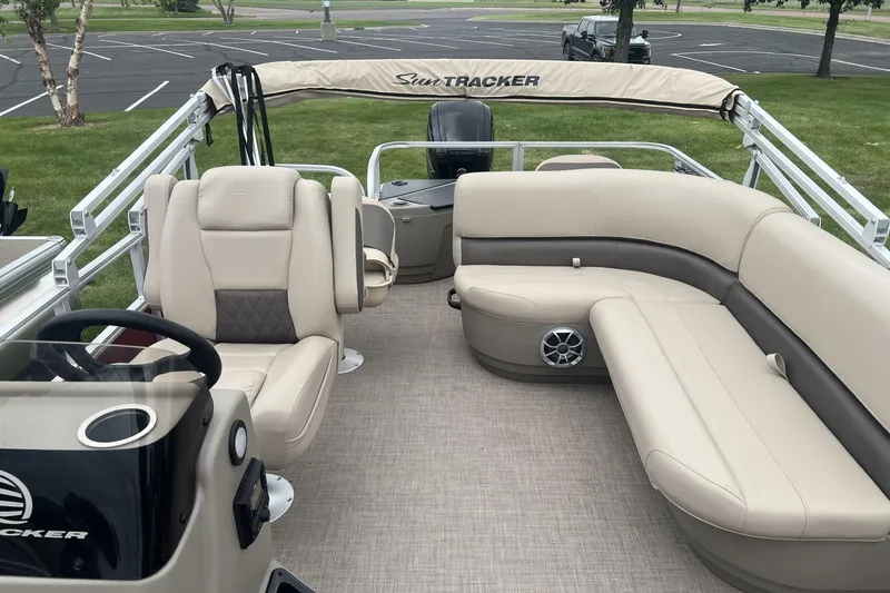 Slide: The Image of 2025 Sun Tracker Bass Buggy 18 DLX pontoon boat interior with beige seating and steering console. - 5