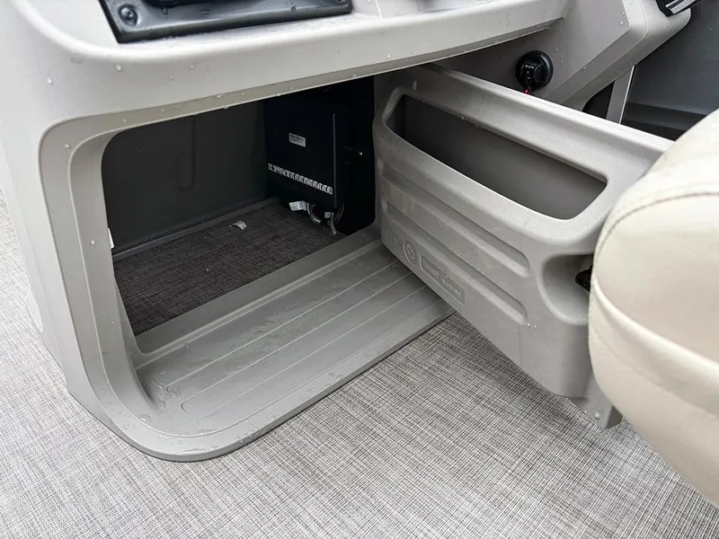 Slide: The Image of 2025 Sun Tracker Fishin' Barge 20 DLX interior storage compartment with gray flooring. - 12
