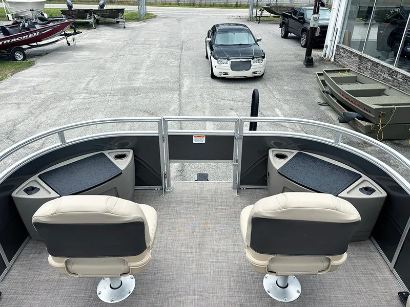 Slide: The Image of 2025 Sun Tracker Fishin' Barge 20 DLX interior with two seats, docked at marina. - 13