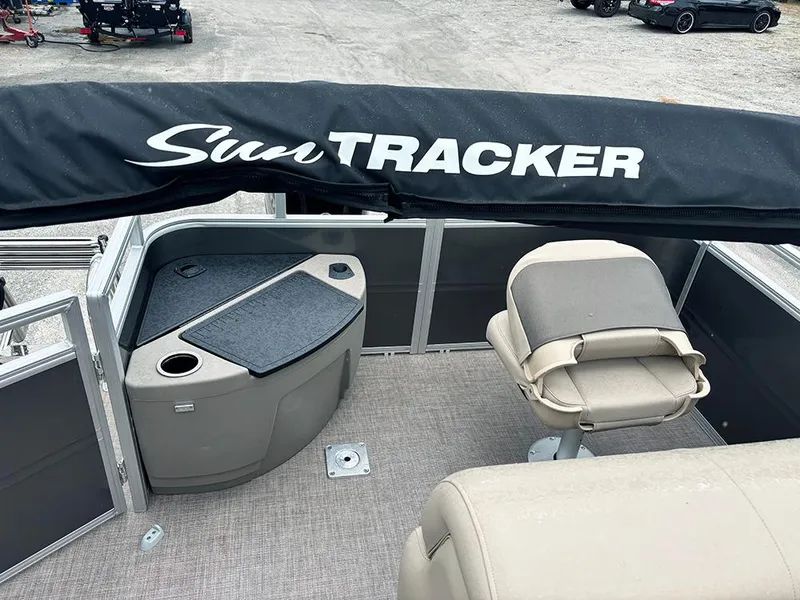 Slide: The Image of 2025 Sun Tracker Fishin' Barge 20 DLX interior with seating and storage, featuring a protective cover. - 20