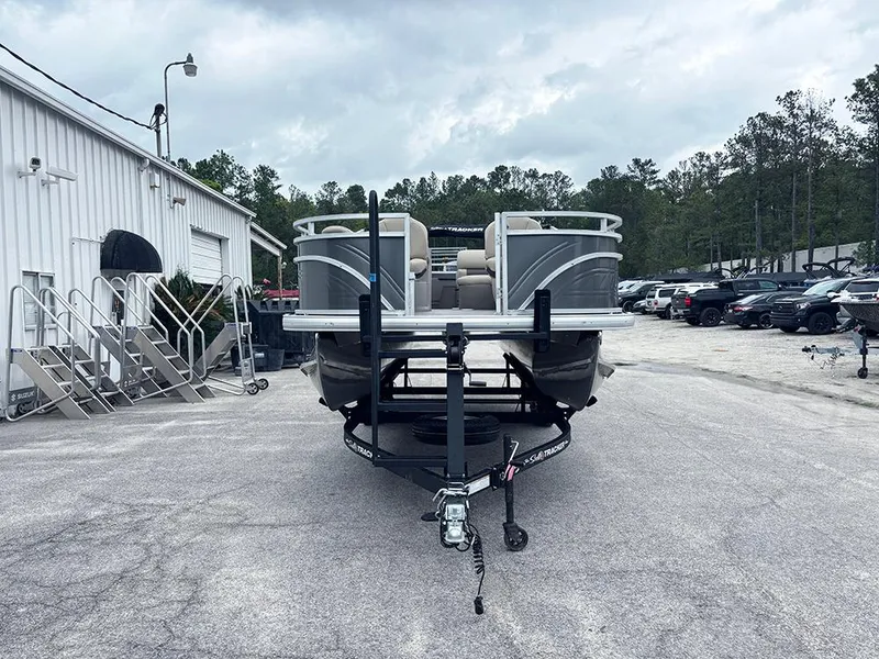Slide: The Image of 2025 Sun Tracker Fishin' Barge 20 DLX pontoon boat on trailer, parked outdoors. - 4