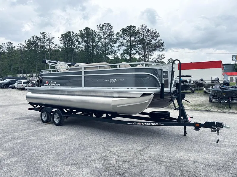 Slide: The Image of 2025 Sun Tracker Fishin' Barge 20 DLX pontoon boat on trailer, parked outdoors. - 5