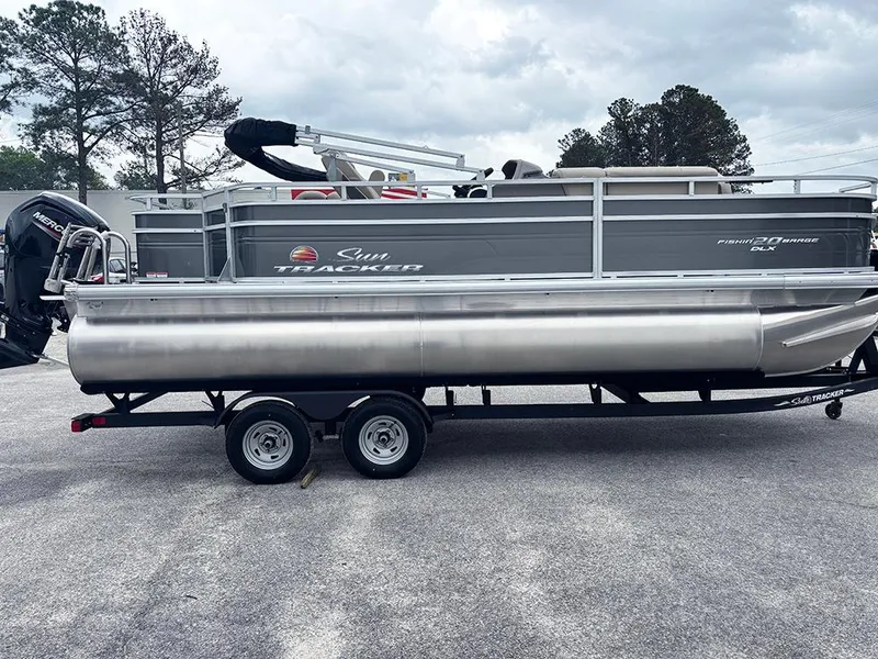 Slide: The Image of 2025 Sun Tracker Fishin' Barge 20 DLX pontoon boat on trailer, parked outdoors. - 6