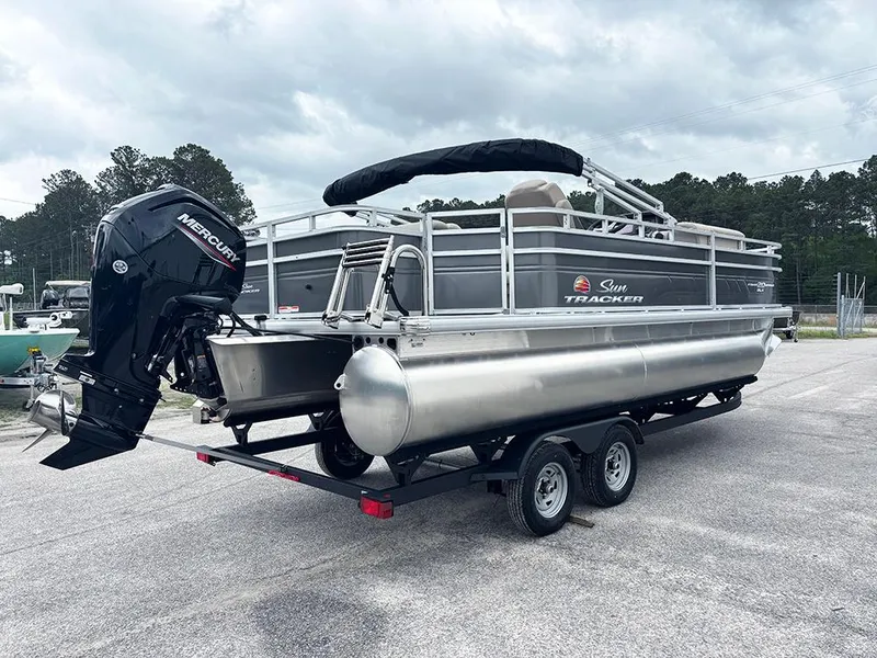 Slide: The Image of 2025 Sun Tracker Fishin' Barge 20 DLX pontoon boat on trailer, featuring Mercury outboard motor. - 7