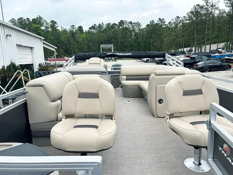 Slide: The Image of 2025 Sun Tracker Fishin' Barge 20 DLX pontoon boat with beige seating, docked outdoors. - 9
