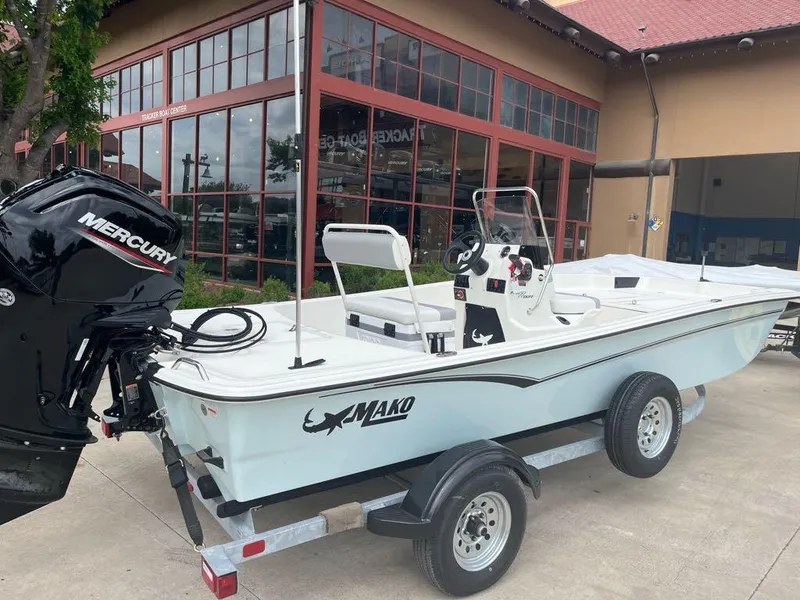 Slide: The Image of 2025 Mako Pro Skiff 17 CC boat on trailer with Mercury engine, parked outside showroom. - 4