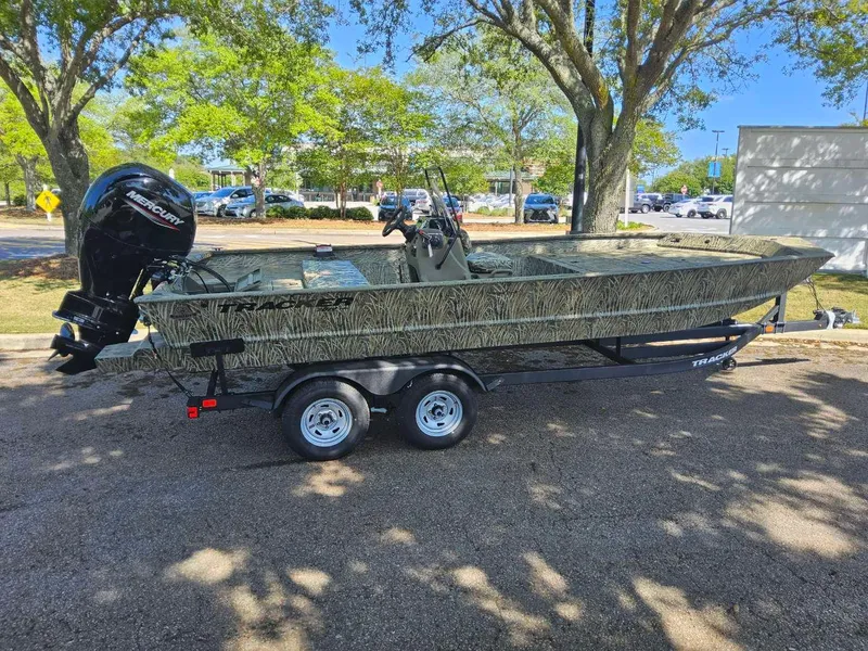 Slide: The Image of 2025 Tracker Grizzly 2072 CC boat on trailer, parked outdoors under trees. - 2