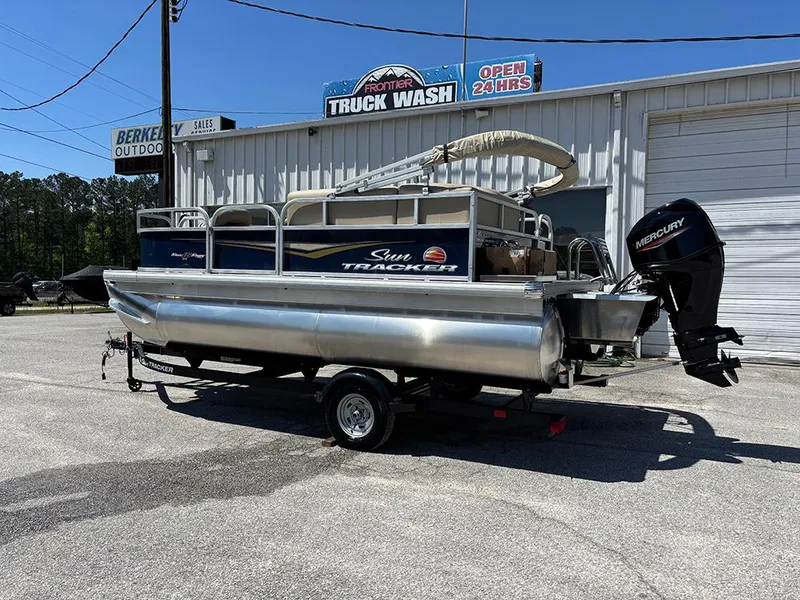 Slide: The Image of 2025 Sun Tracker Bass Buggy 16 XL Select pontoon boat on trailer, parked outside a truck wash. - 3