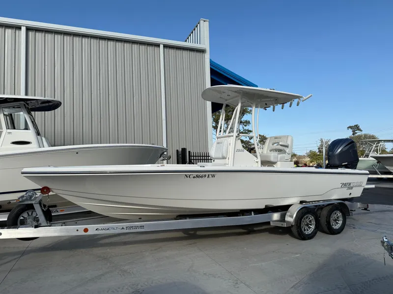 Slide: The Image of 2022 Pathfinder 2500 Hybrid boat on trailer, parked outside a metal building. - 0