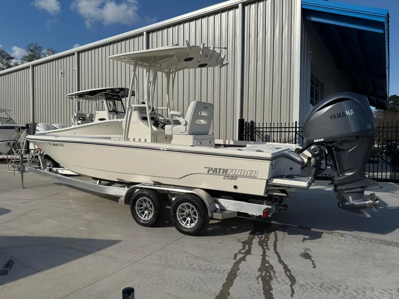 Slide: The Image of 2022 Pathfinder 2500 Hybrid boat on trailer, parked outdoors near a metal building. - 1