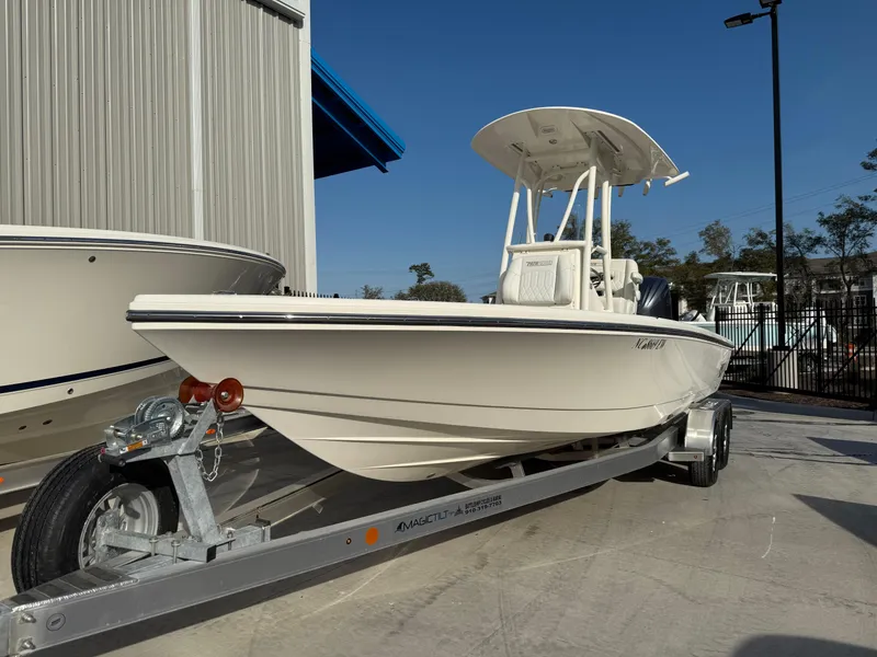 Slide: The Image of 2022 Pathfinder 2500 Hybrid boat on trailer, parked outdoors under clear blue sky. - 2