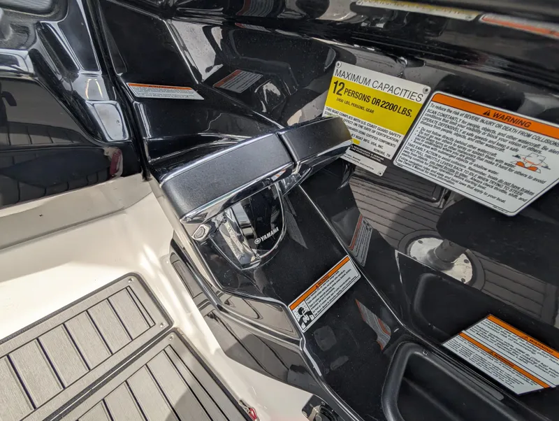Slide: The Image of 2017 Yamaha Boats 242X E-Series interior with capacity warning labels and sleek black finish. - 26
