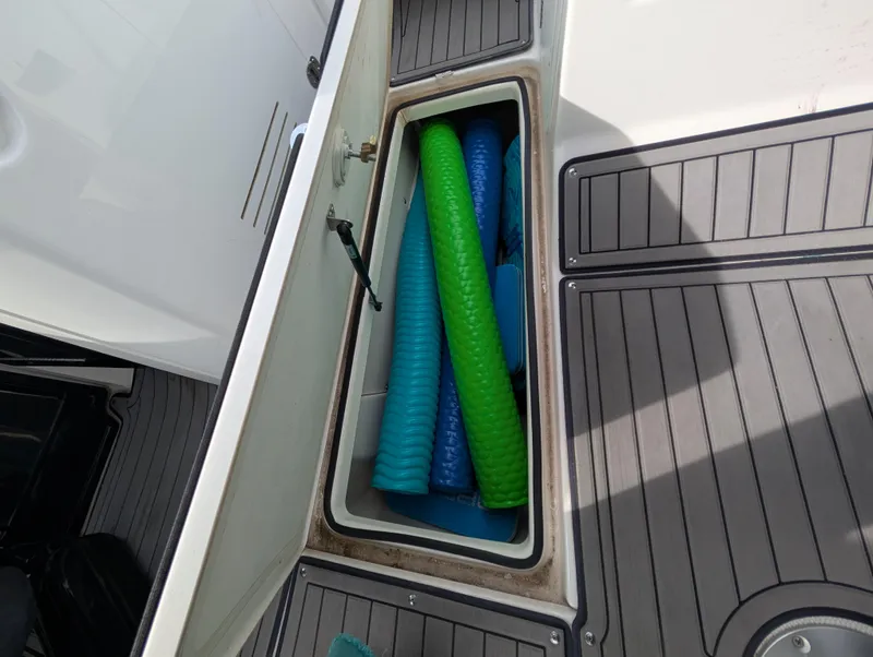 Slide: The Image of Storage compartment on 2017 Yamaha Boats 242X E-Series with colorful pool noodles. - 29