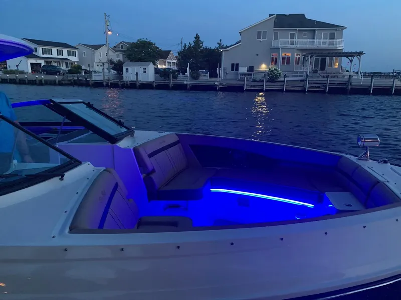 Slide: The Image of 2017 Sea Ray SLX 350 OB boat with blue interior lights, docked near waterfront homes. - 32
