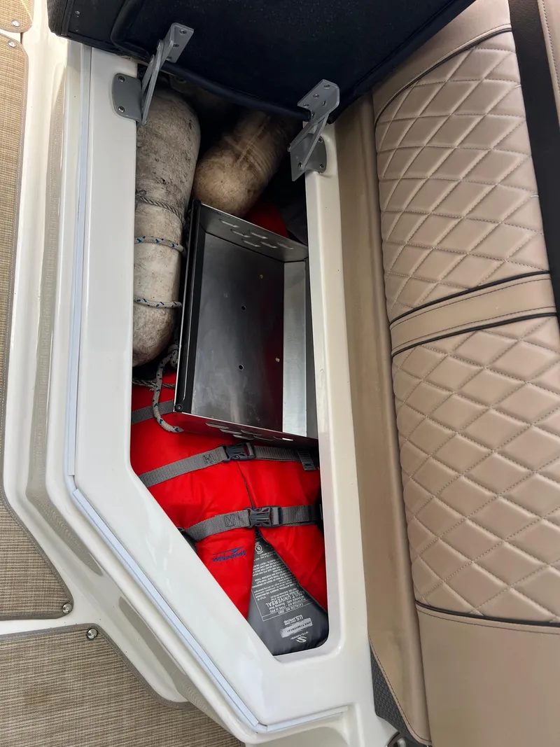 Slide: The Image of Storage compartment in a 2017 Sea Ray SLX 350 OB with life jacket and accessories. - 45