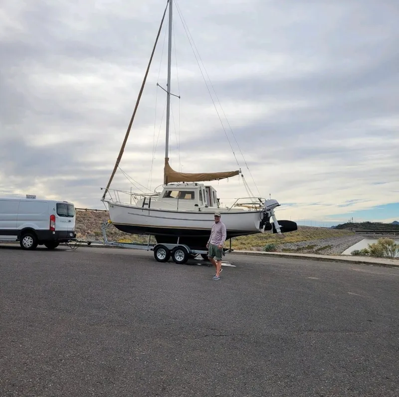 Slide: The Image of 2022 Com-Pac CP 23 Pilothouse sailboat on trailer, parked near a van. - 10