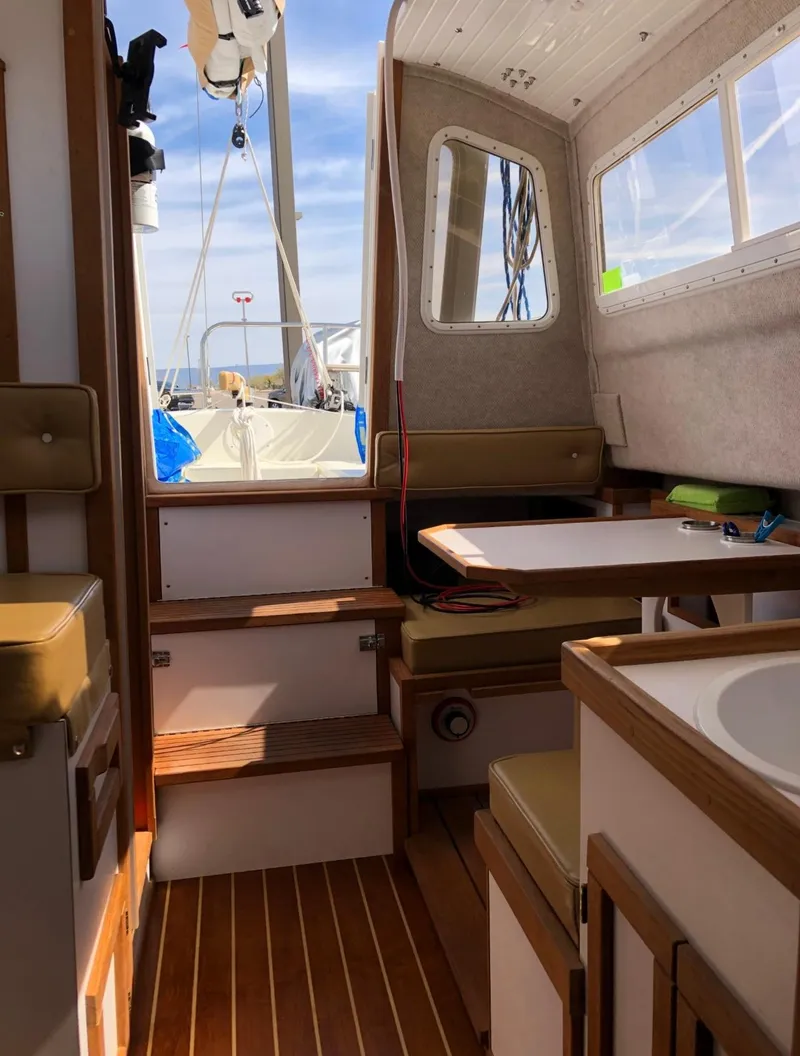 Slide: The Image of 2022 Com-Pac CP 23 Pilothouse interior with wooden flooring and seating area. - 15