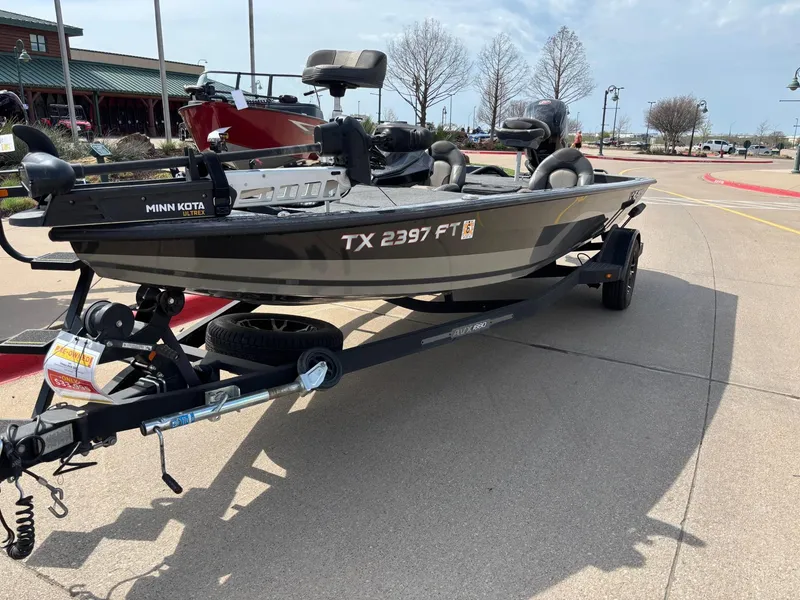 Slide: The Image of 2020 Vexus AVX1880 boat on trailer, parked outdoors, featuring Minn Kota trolling motor. - 2