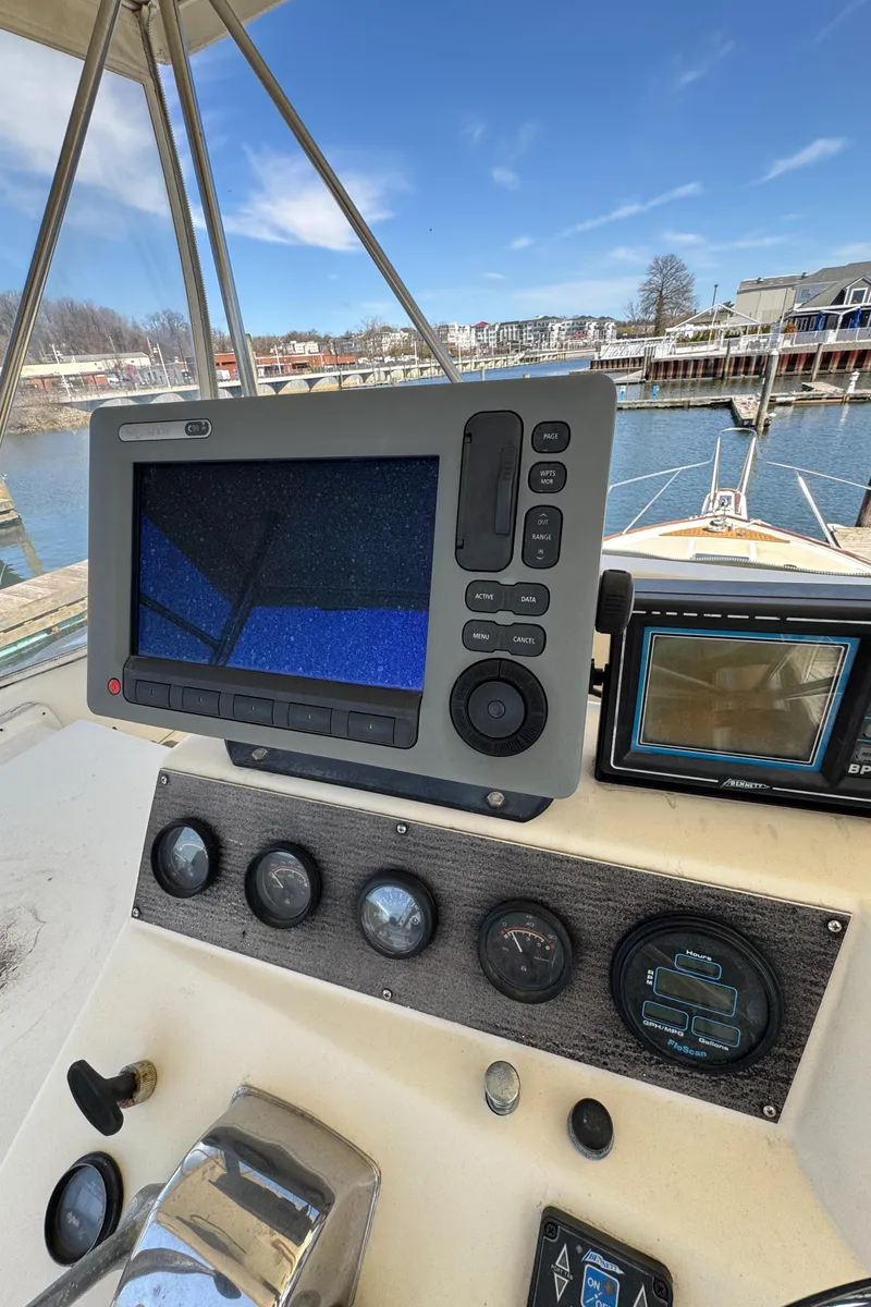 Slide: The Image of 1985 Egg Harbor Convertible boat dashboard with navigation equipment, docked at a marina. - 12