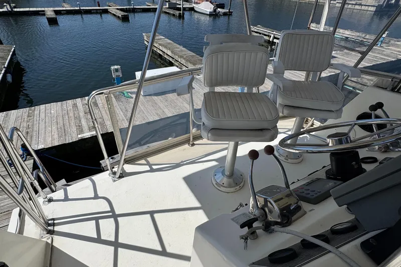 Slide: The Image of 1985 Egg Harbor Convertible boat helm with white seats at a marina dock. - 9