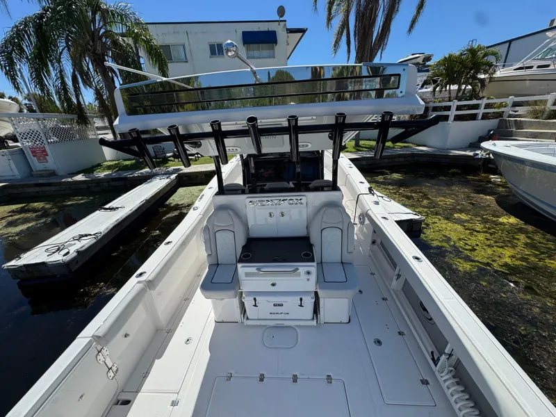 Slide: The Image of 2022 Sea Fox 368 Commander boat interior with seating and storage, docked near palm trees. - 37