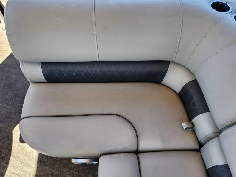 Slide: The Image of 2023 Sun Tracker Fishin' Barge 20 DLX boat seating, beige and gray upholstery, cup holder visible. - 18