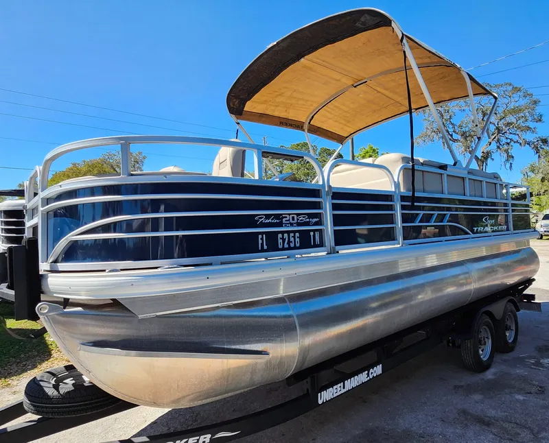 Slide: The Image of 2023 Sun Tracker Fishin' Barge 20 DLX pontoon boat on trailer, side view. - 3