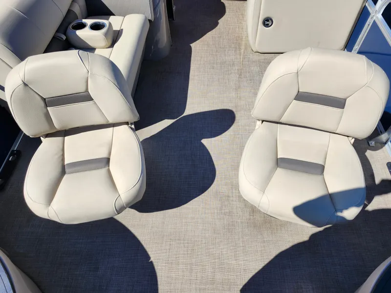 Slide: The Image of 2023 Sun Tracker Fishin' Barge 20 DLX interior with beige seating and cup holders. - 30