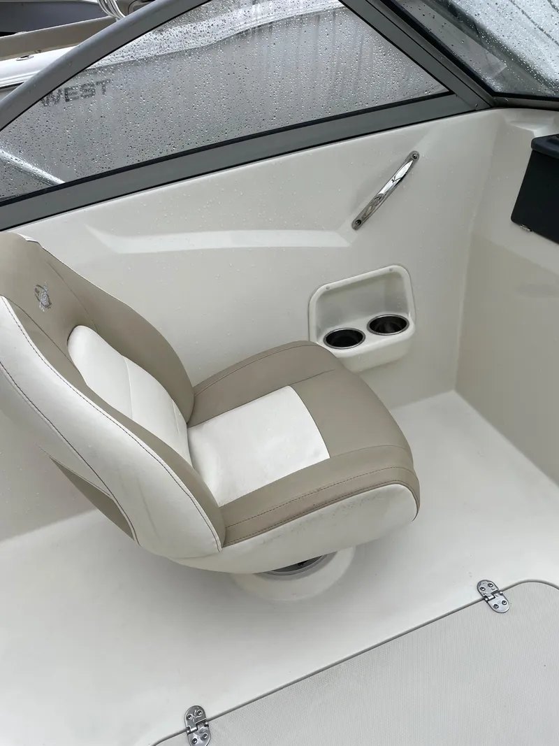 Slide: The Image of 2017 Stingray 191 DC boat interior with beige and white seat, cup holders, and window. - 12