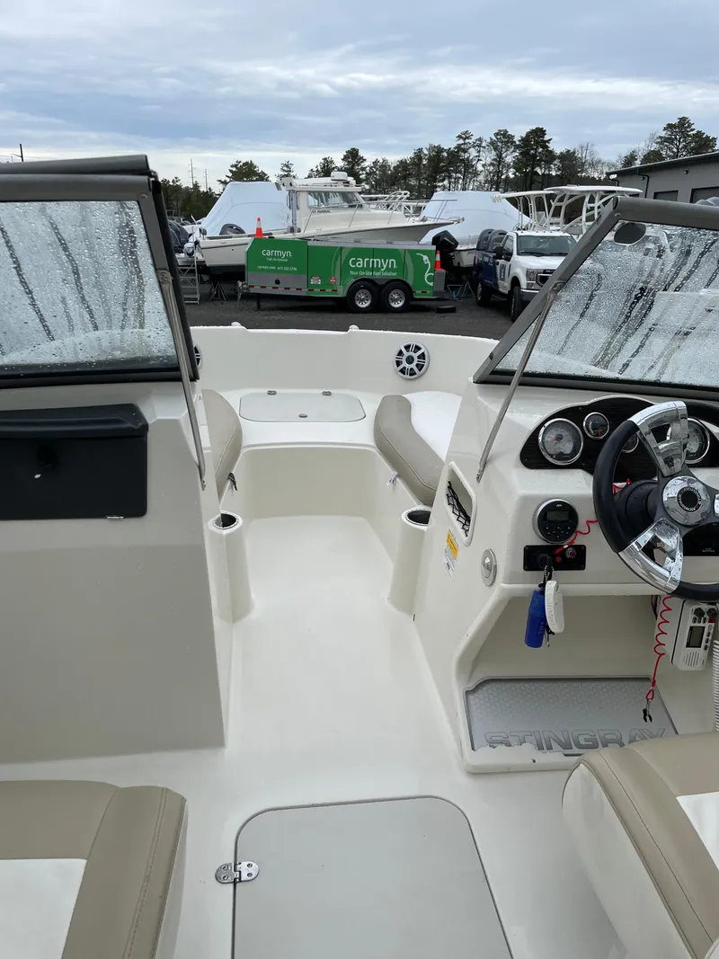 Slide: The Image of 2017 Stingray 191 DC boat interior with steering wheel and seating, parked outdoors. - 15