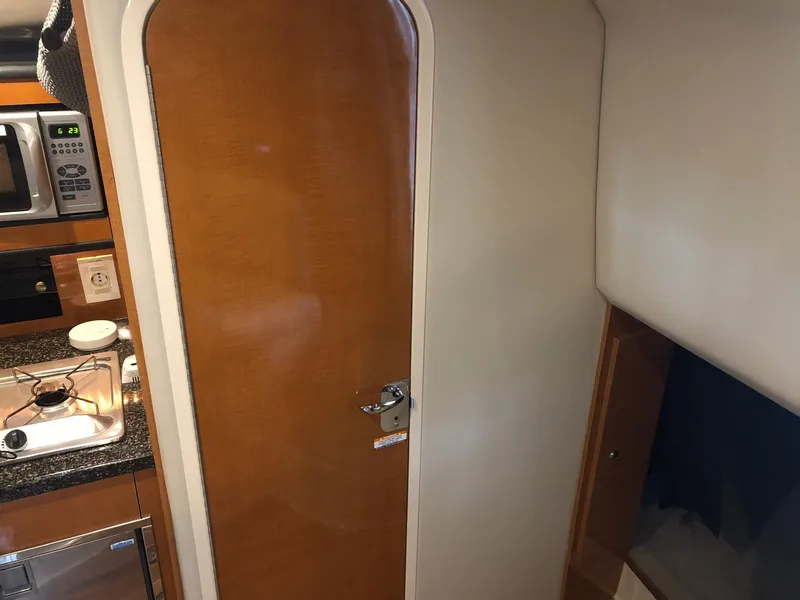 Slide: The Image of Interior of 2008 Chaparral 310 Signature boat, featuring a wooden door and kitchenette. - 24