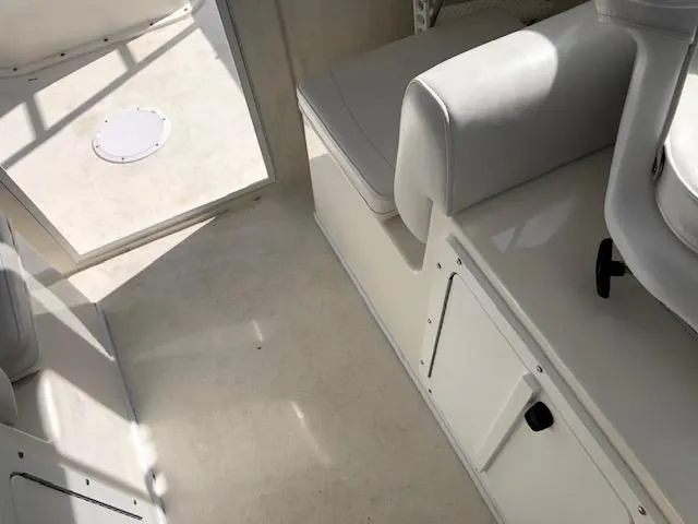 Slide: The Image of Interior of 2022 May-Craft 2700 Pilot House, featuring white seating and storage compartments. - 18
