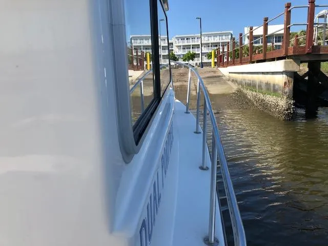 Slide: The Image of 2022 May-Craft 2700 Pilot House boat docked near a waterfront building. - 24