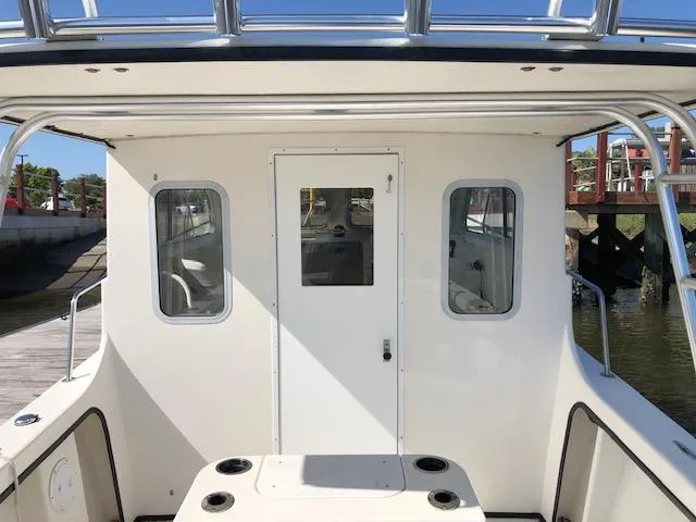 Slide: The Image of 2022 May-Craft 2700 Pilot House boat, rear view, docked, showcasing cabin entrance and windows. - 7