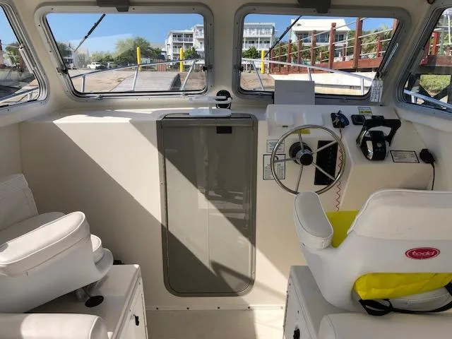 Slide: The Image of Interior of 2022 May-Craft 2700 Pilot House boat, featuring steering wheel and seating. - 9